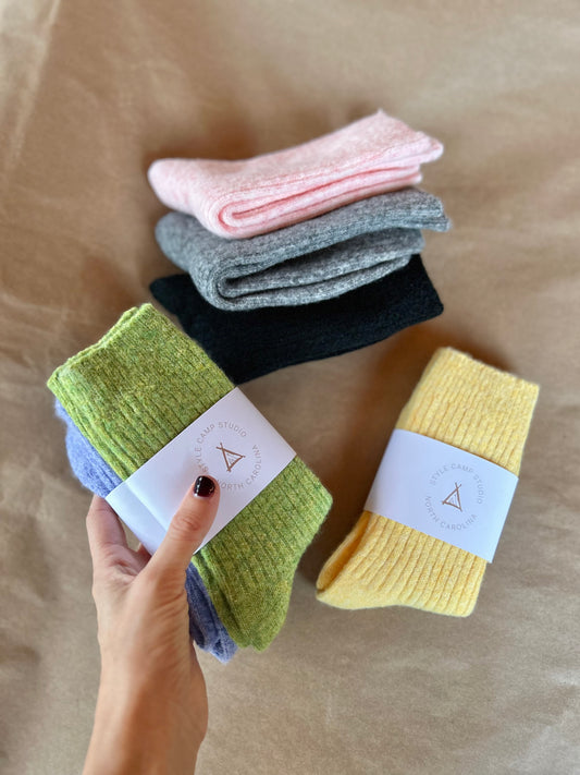 Stack of colorful socks with a hand holding them on a brown surface