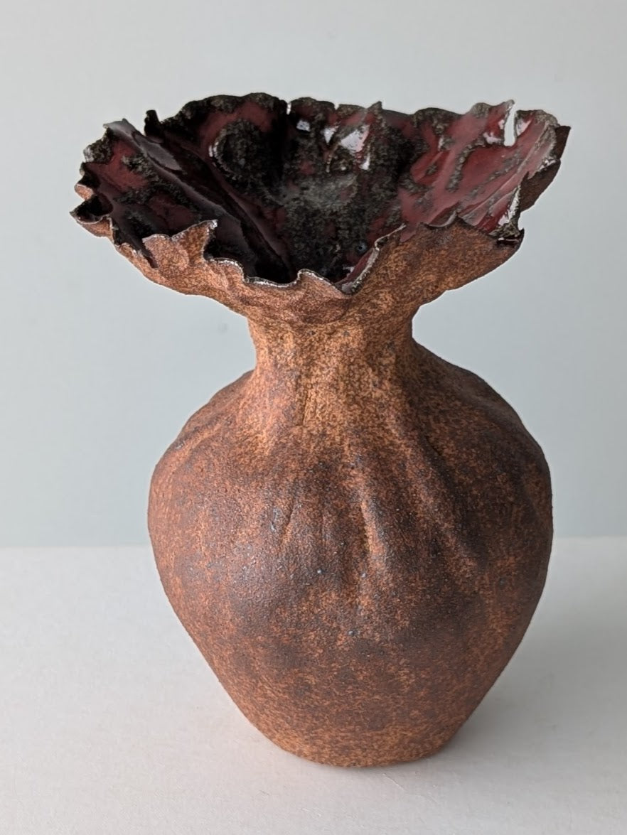 Bronze vase with textured surface and wavy rim on a white background