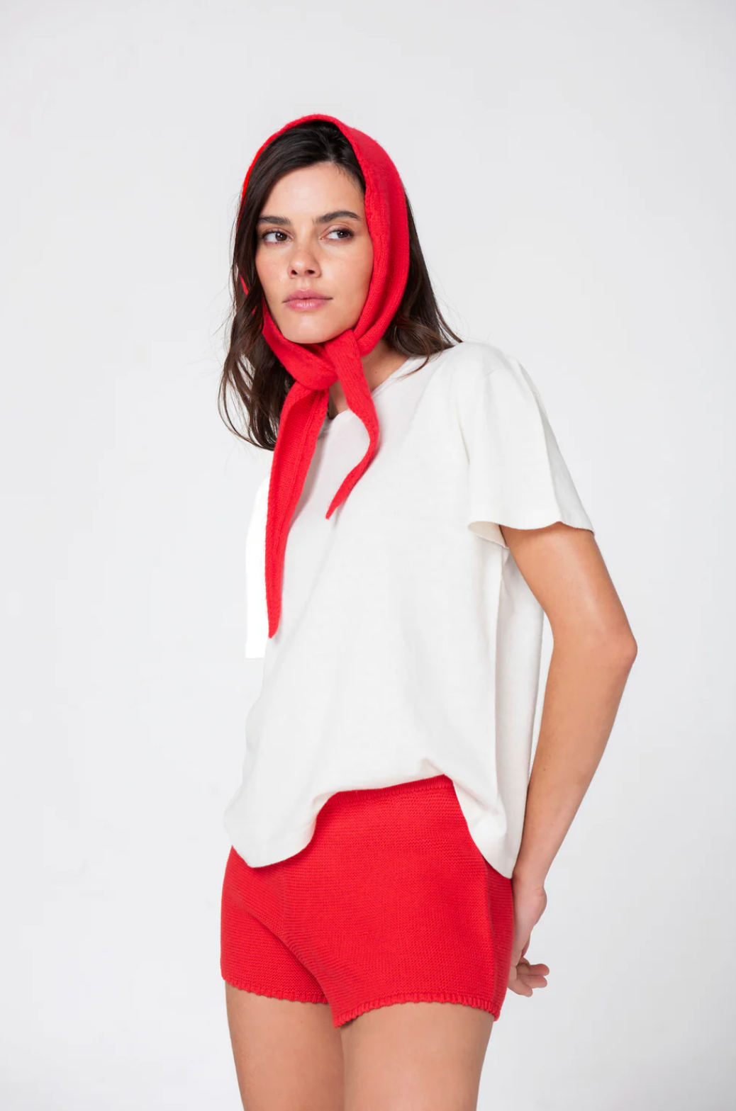 Woman wearing a white top and red shorts with a red headscarf on a white background