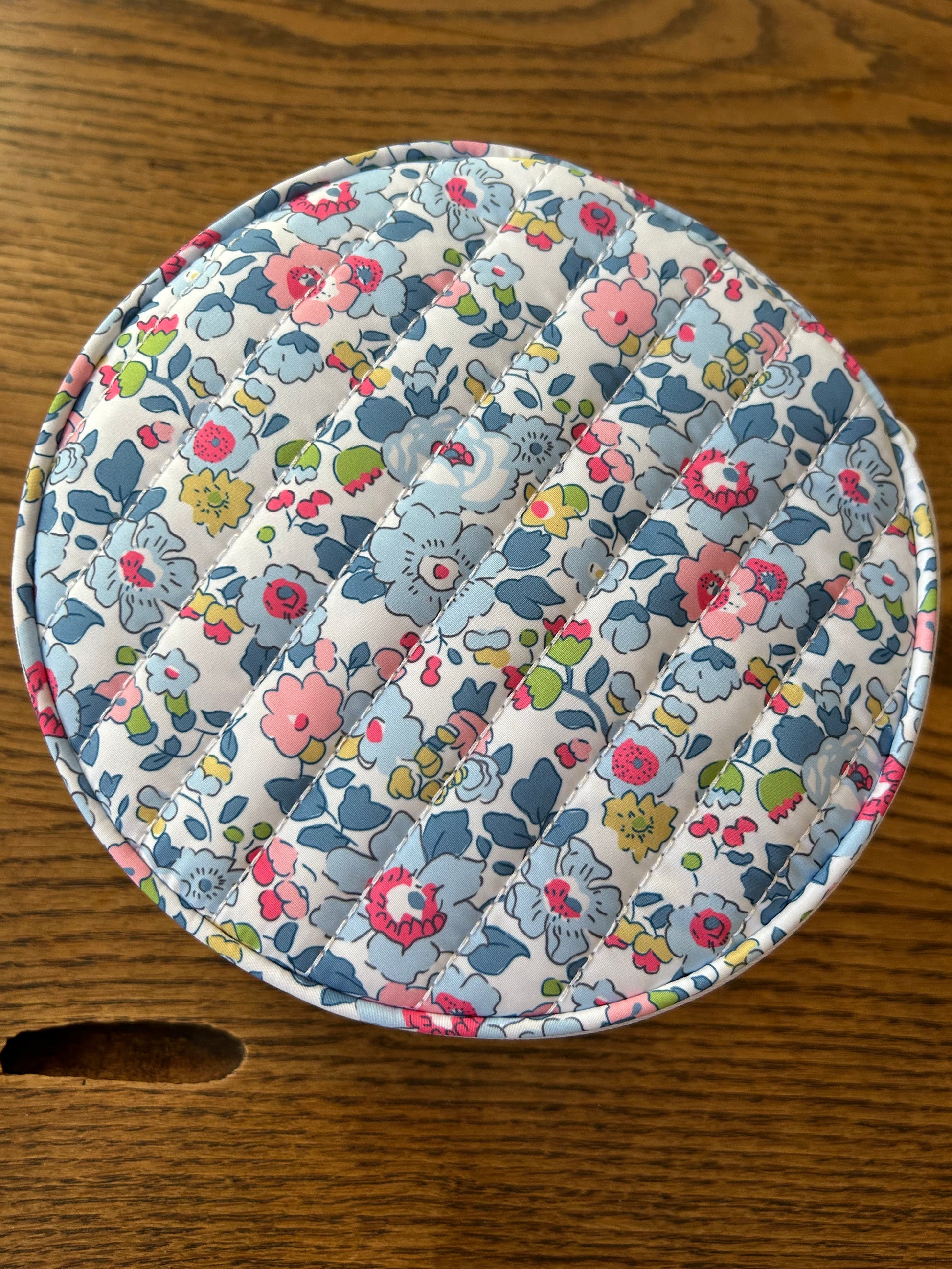 Floral patterned travel jewelry case on a wooden surface