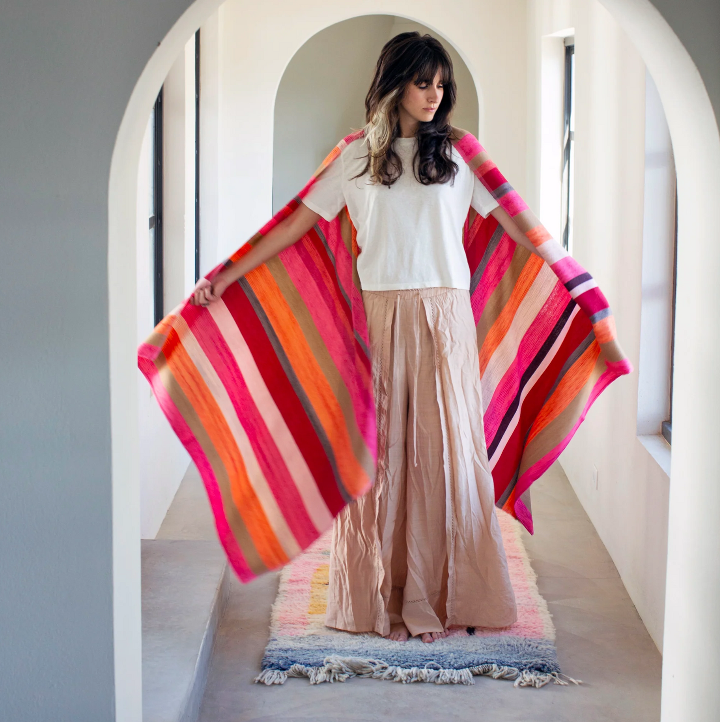 Woman holding a colorful striped scarf in a bright room