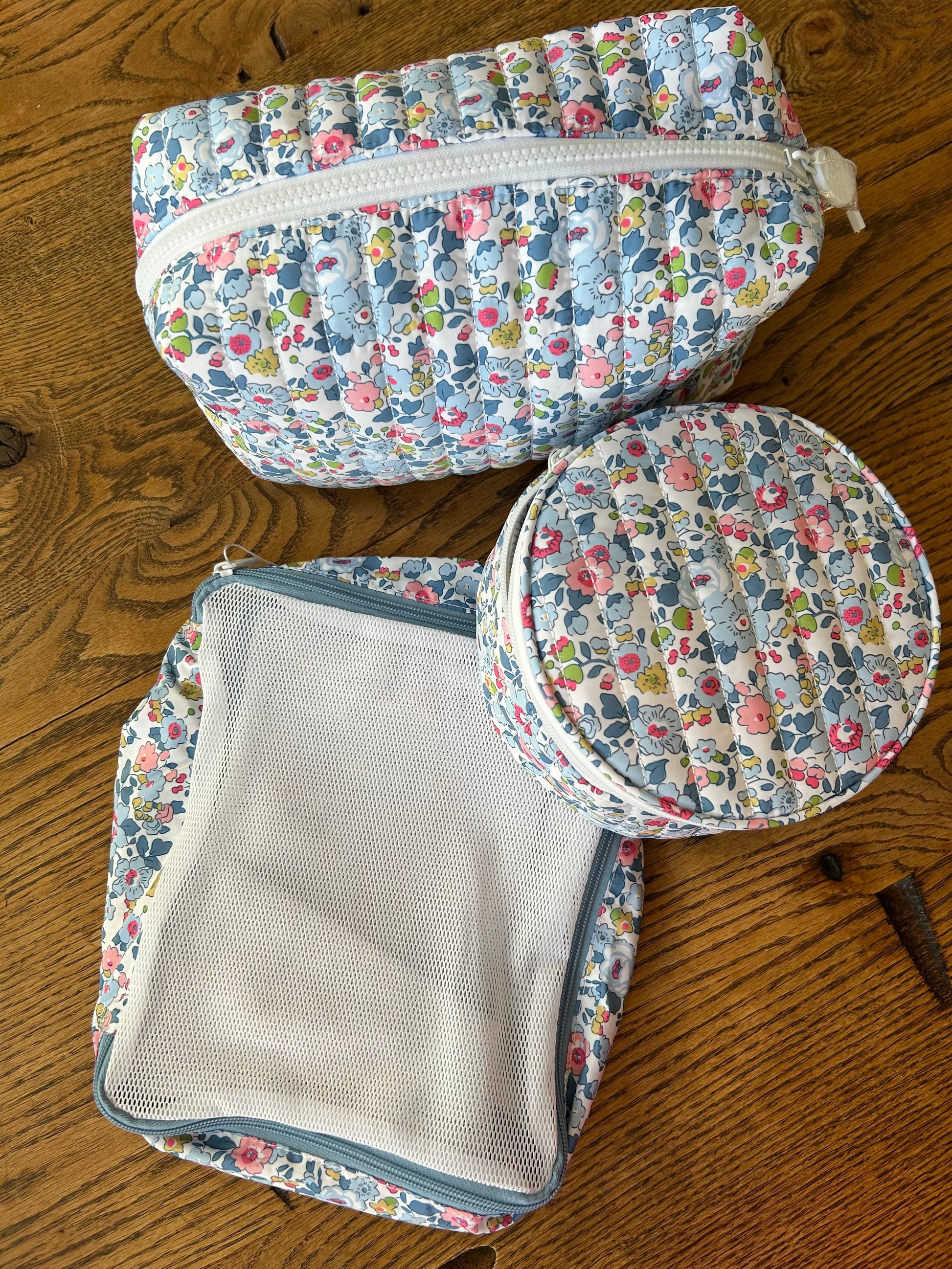 Set of floral-patterned packing cubes on a wooden surface